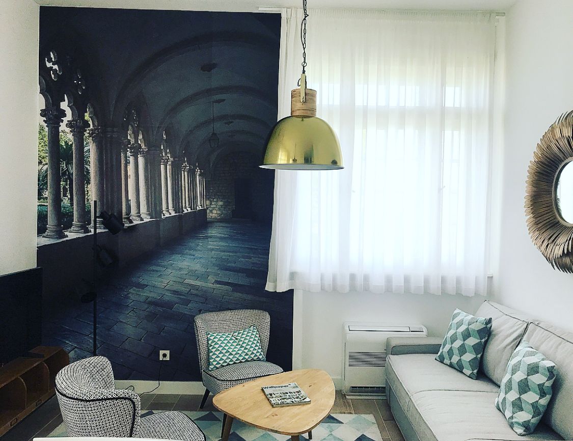 A living room with a large painting, a sofa, two armchairs, a coffee table, and a hanging lamp.