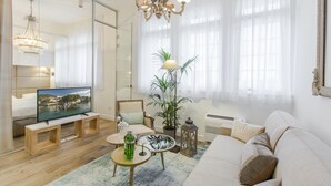 A modern living room with a television, sofa, coffee table, and potted plants. - Ah Design Apartments (Opatija)