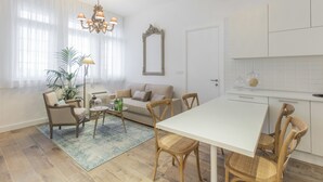 A modern living room with a sofa, chairs, a dining table, and a kitchen area. - Ah Design Apartments (Opatija)