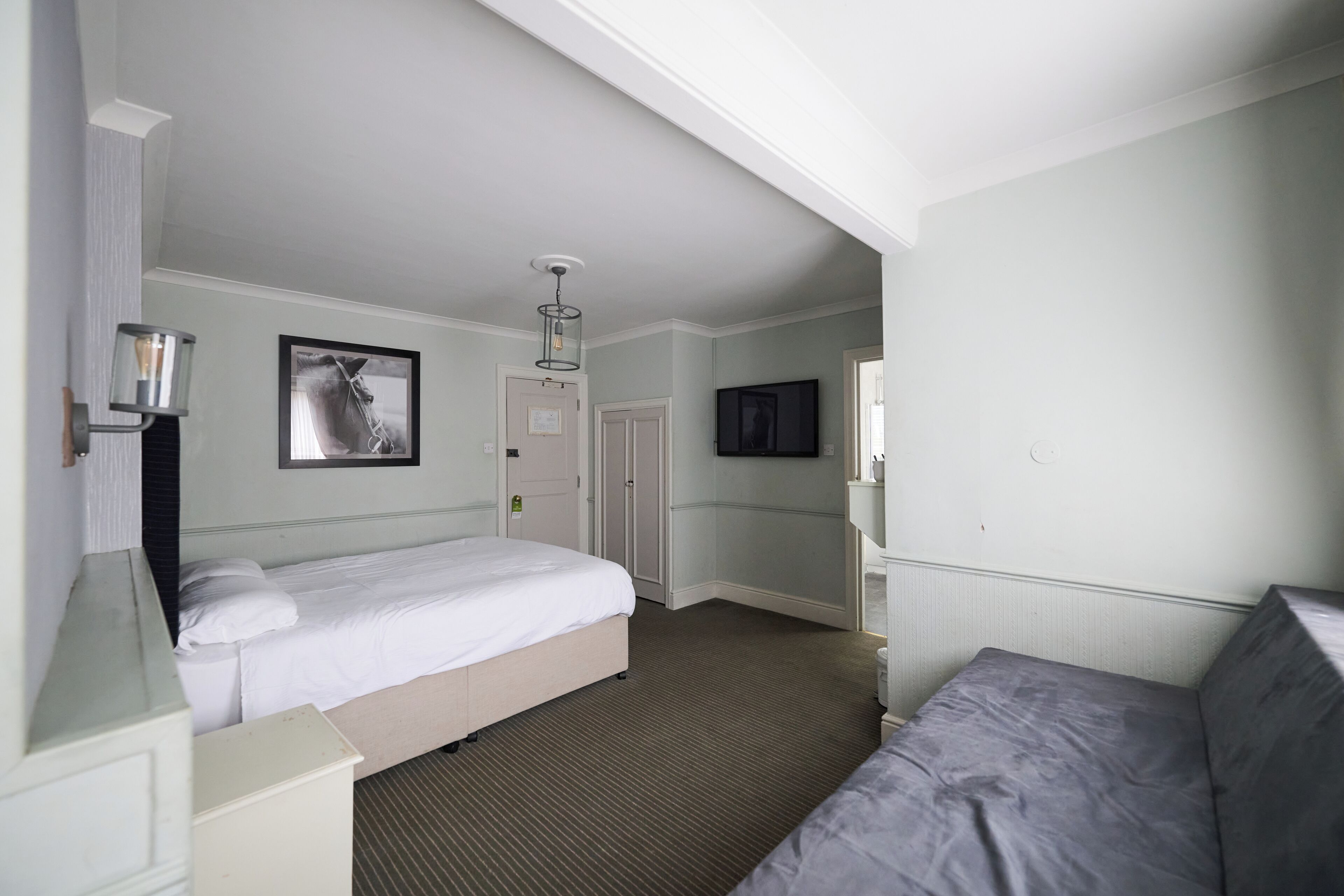 Een hotelkamer met een bed, een televisie, een deur en een lamp.