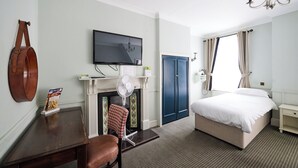 A hotel room with a bed, a television, a fireplace, a desk, and a chair. - White Hart, Newmarket by Marston's Inns (Newmarket)