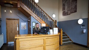 A hotel reception desk with a wooden counter, a computer, and a sign indicating hotel rooms. - White Hart, Newmarket by Marston's Inns (Newmarket)