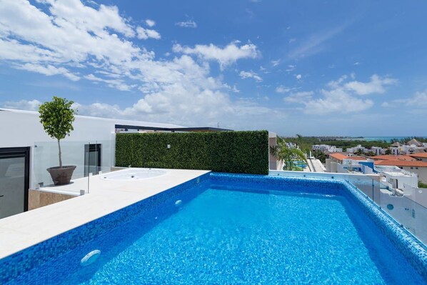 A rooftop infinity pool with a clear view of the cityscape. - Menesse 205 by CocoBR (Playa del Carmen)