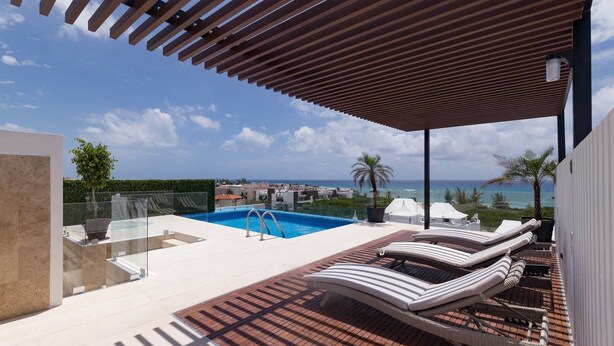 A rooftop pool area with lounge chairs and a view of the ocean.