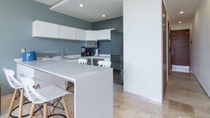 A modern kitchen with white cabinets, a central island with bar stools, and a microwave.