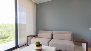A modern living room with a sofa, a coffee table with a plant, and two side tables.