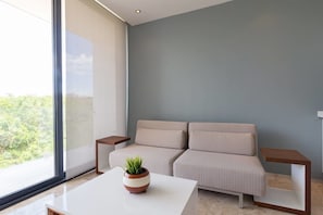 A modern living room with a sofa, a coffee table with a plant, and two side tables.