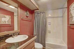 A bathroom with a white sink, a mirror, a shower curtain, and a toilet. - Pines 2045 (Keystone)
