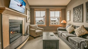 A living room with a fireplace, a television, a sofa, and a coffee table. - Silver Mill 8311 (Keystone)