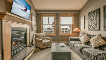 Una sala de estar con chimenea, televisor, sofá y mesa de centro.