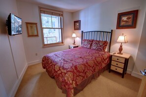 A bedroom with a bed, two bedside tables, a window, and wall-mounted artwork. - Silver Mill 8227 (Keystone)