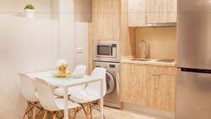 Una cocina moderna con armarios de madera, un refrigerador de acero inoxidable, un horno empotrado y una lavadora.