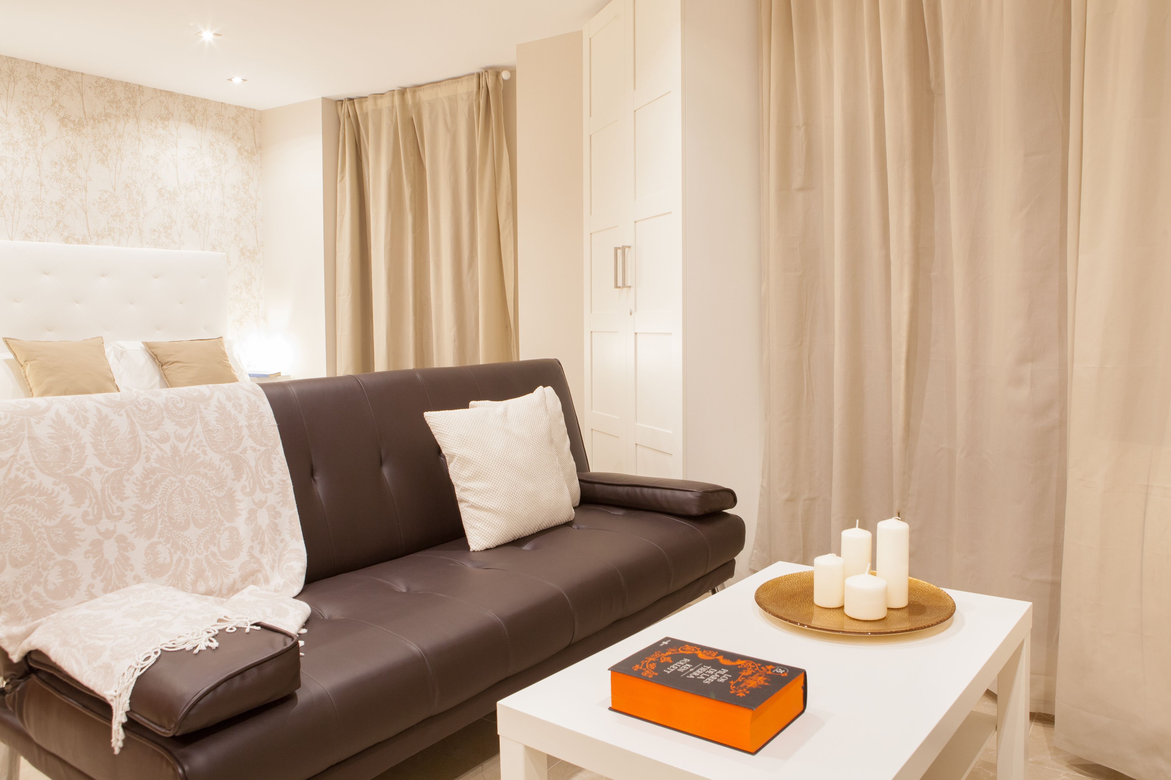A modern living room with a brown leather sofa, a white coffee table, and a book.