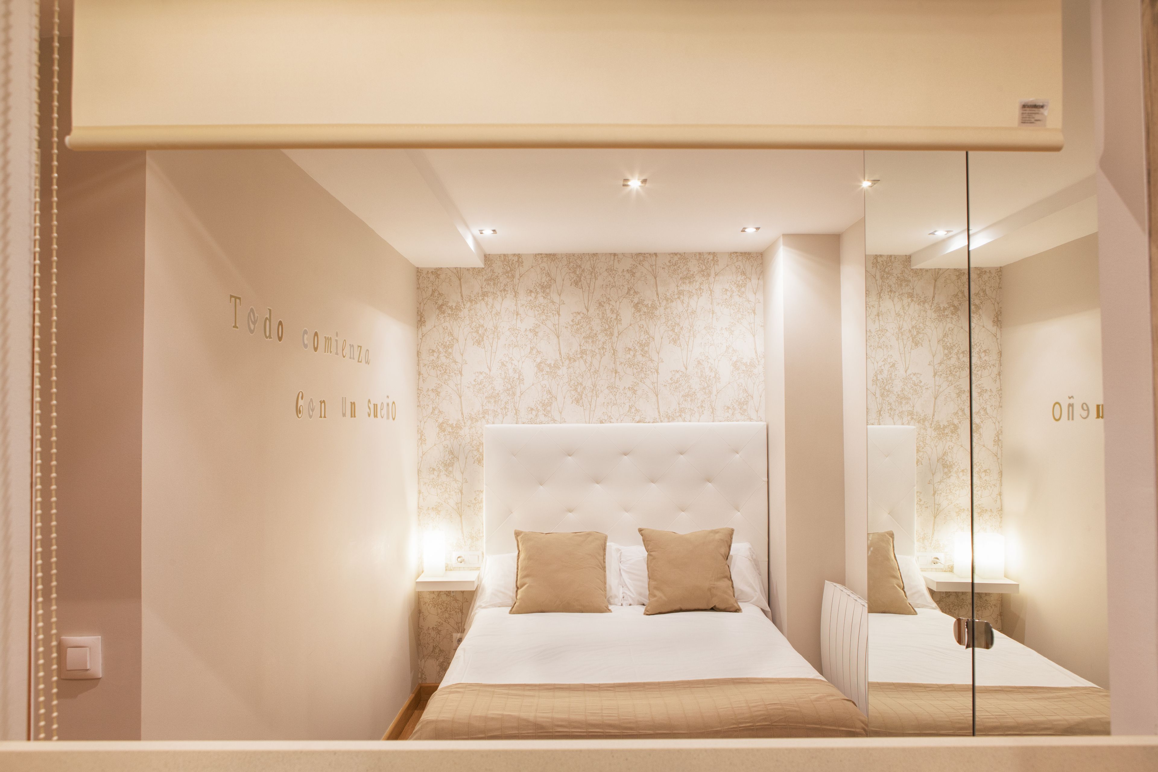 A modern bedroom with a large bed, two bedside tables, and a mirror.