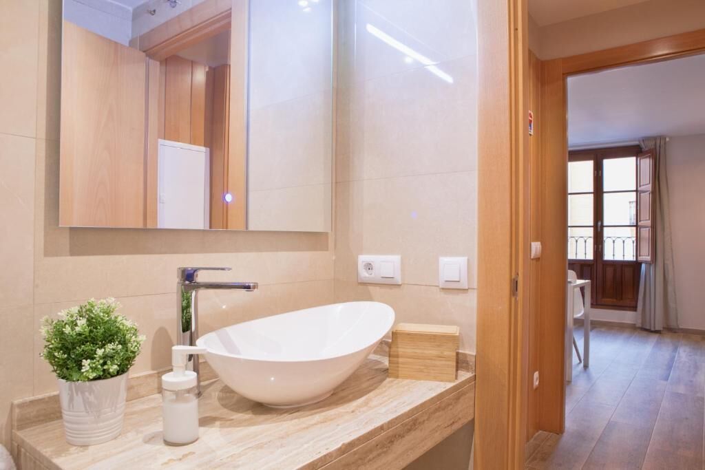 A modern bathroom with a freestanding bathtub, a large mirror, and a potted plant on the vanity.