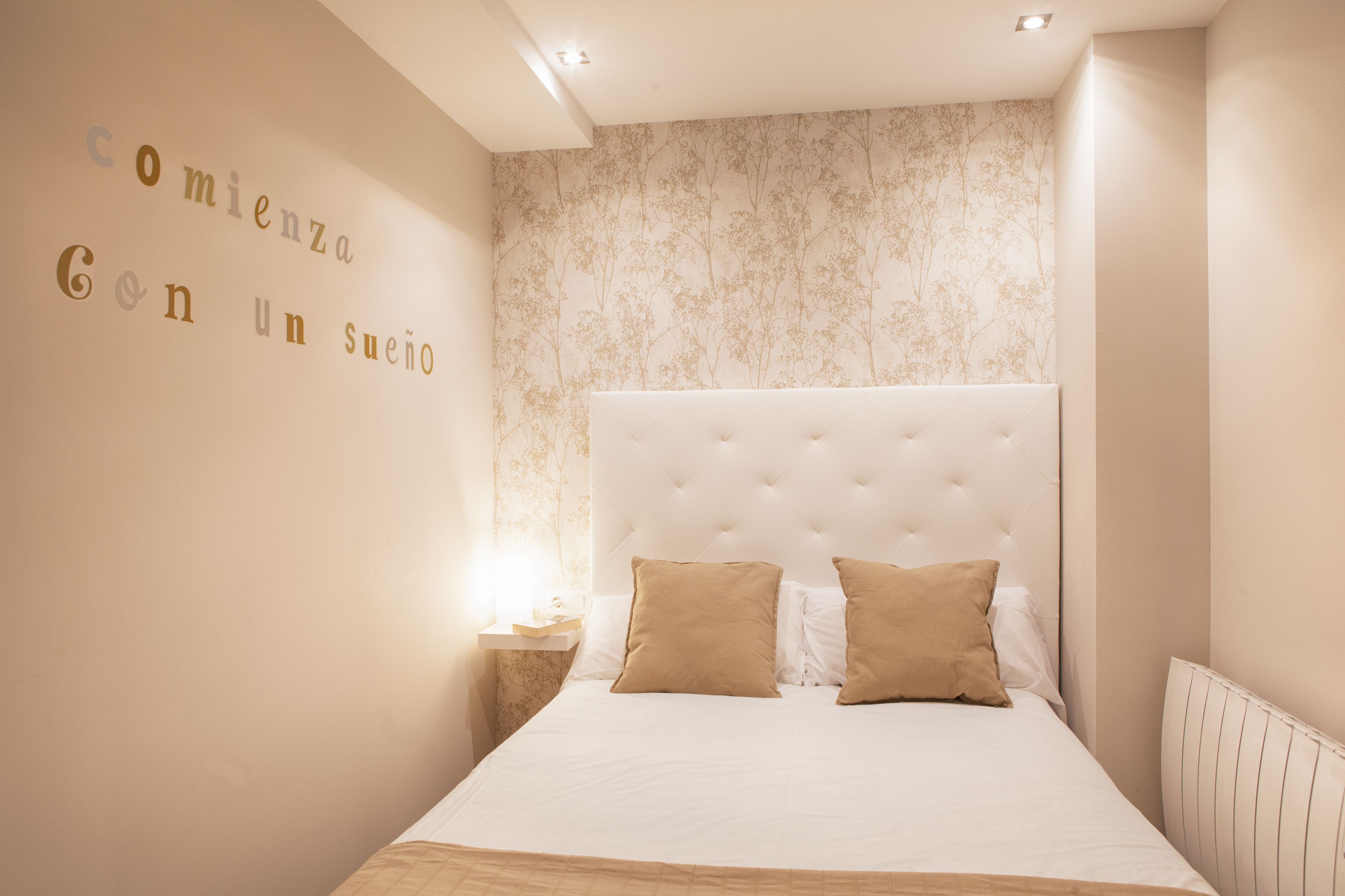 Un dormitorio con una cama grande, una mesita de noche y una pared con estampado floral.