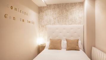 Een slaapkamer met een groot bed, een nachtkastje en een wand met bloemenprint.