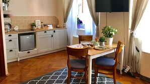 Une cuisine compacte avec un coin repas, un téléviseur fixé au mur et une fenêtre avec des rideaux.