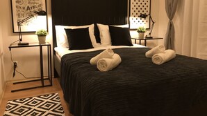 Un lit bien fait, avec une literie noire et blanche, deux tables de chevet avec des lampes et un tapis à motifs.