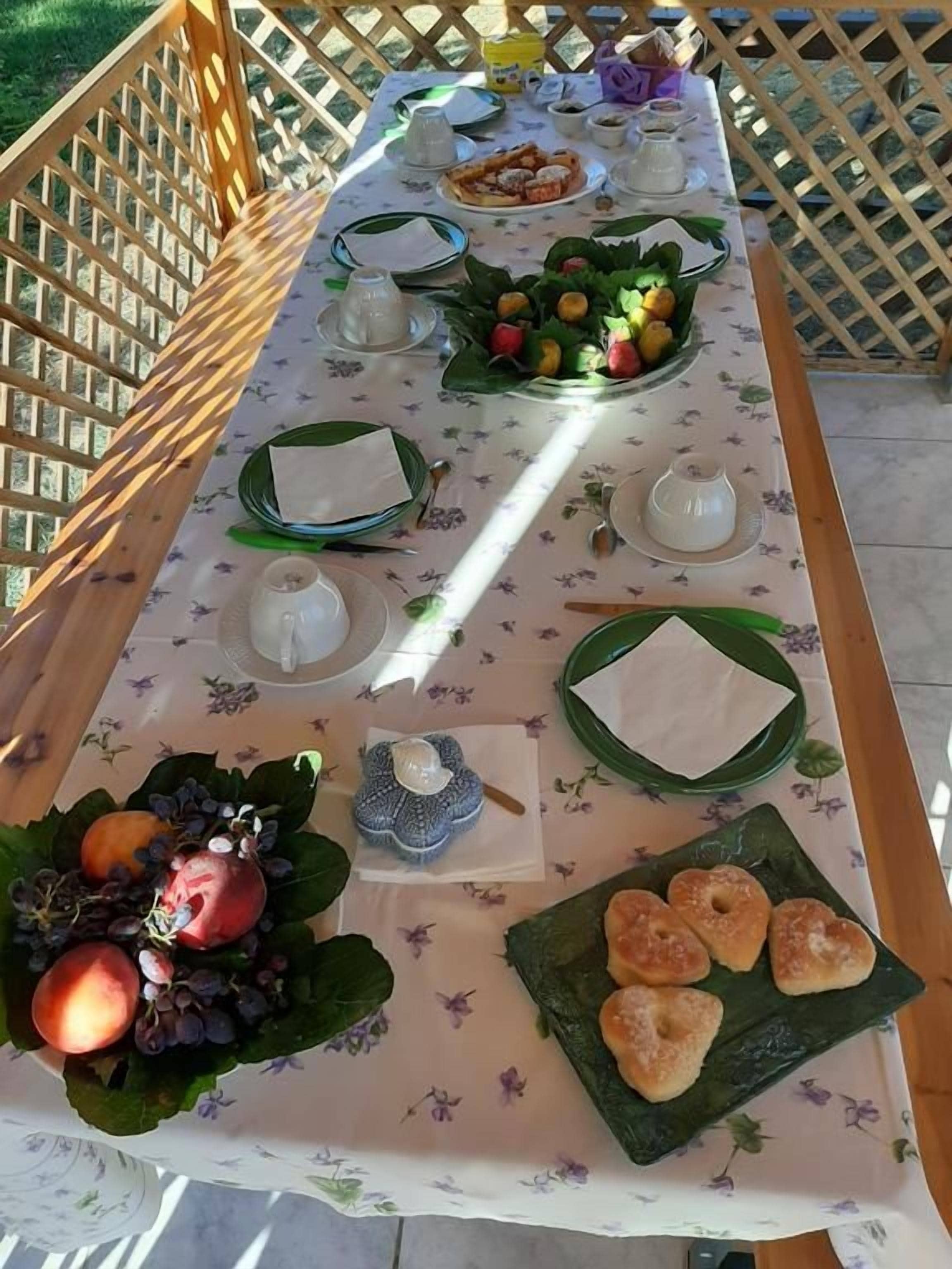 A table set for a meal with plates, cups, and a fruit arrangement.