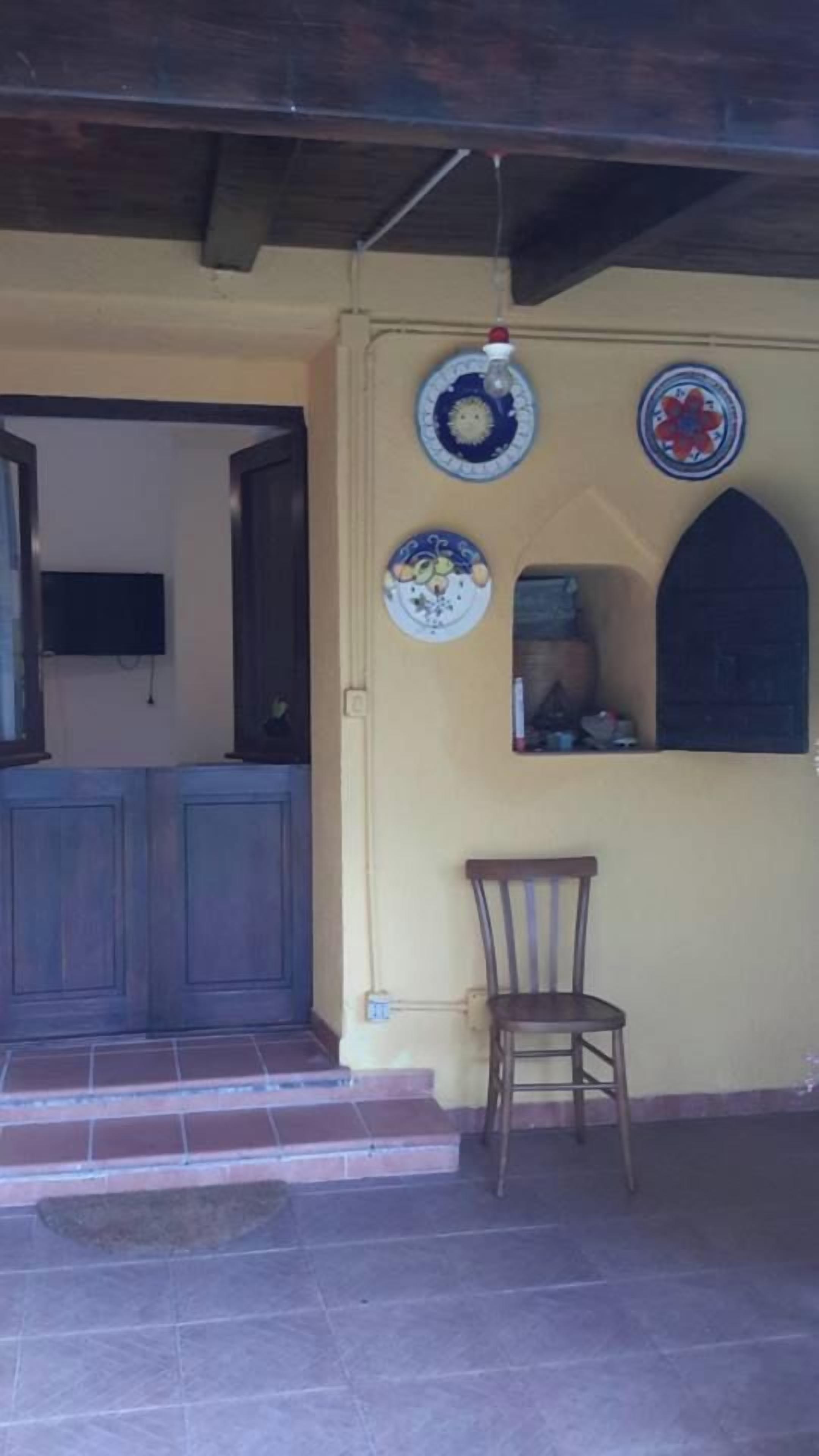 Una habitación con puerta de madera, una silla y una pared decorada con platos.