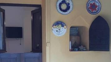 Una habitación con puerta de madera, una silla y una pared decorada con platos.