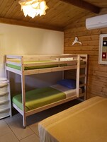 Una cama litera con colchón verde, un archivador blanco y un aire acondicionado de pared.