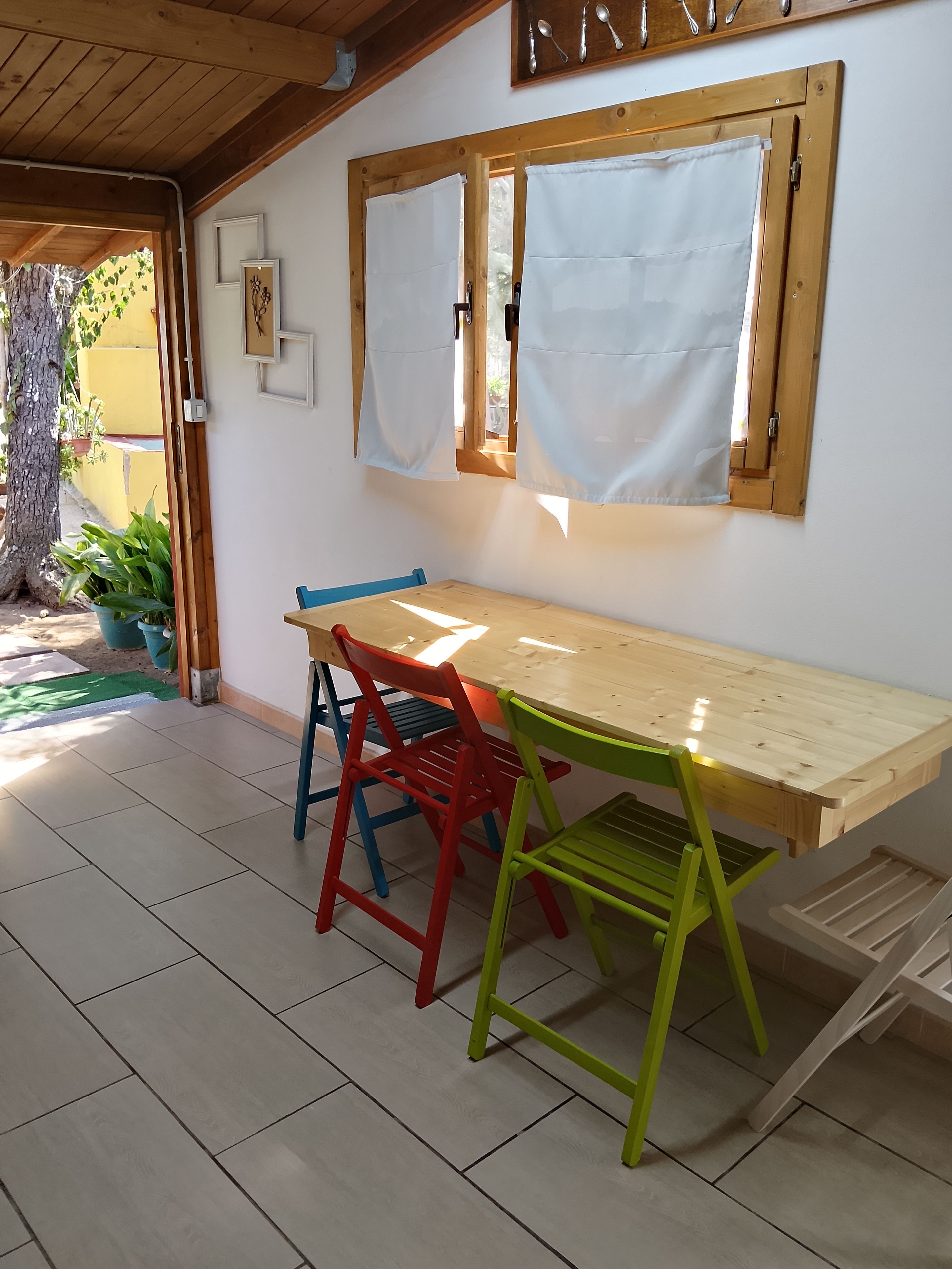 A wooden table with chairs, a window with curtains, and a potted plant.