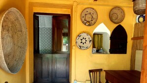 A yellow-walled entrance with a dark wooden door, a small table, and two chairs. - Casa di Campagna Dal Pozzo (Sorso)
