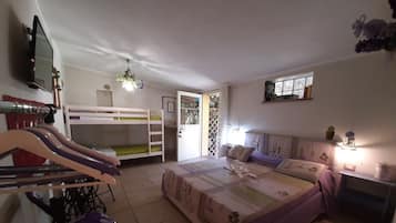 Camera da letto con letti a castello, un letto con copriletto floreale, una scrivania con sedia, una televisione e un lampadario.