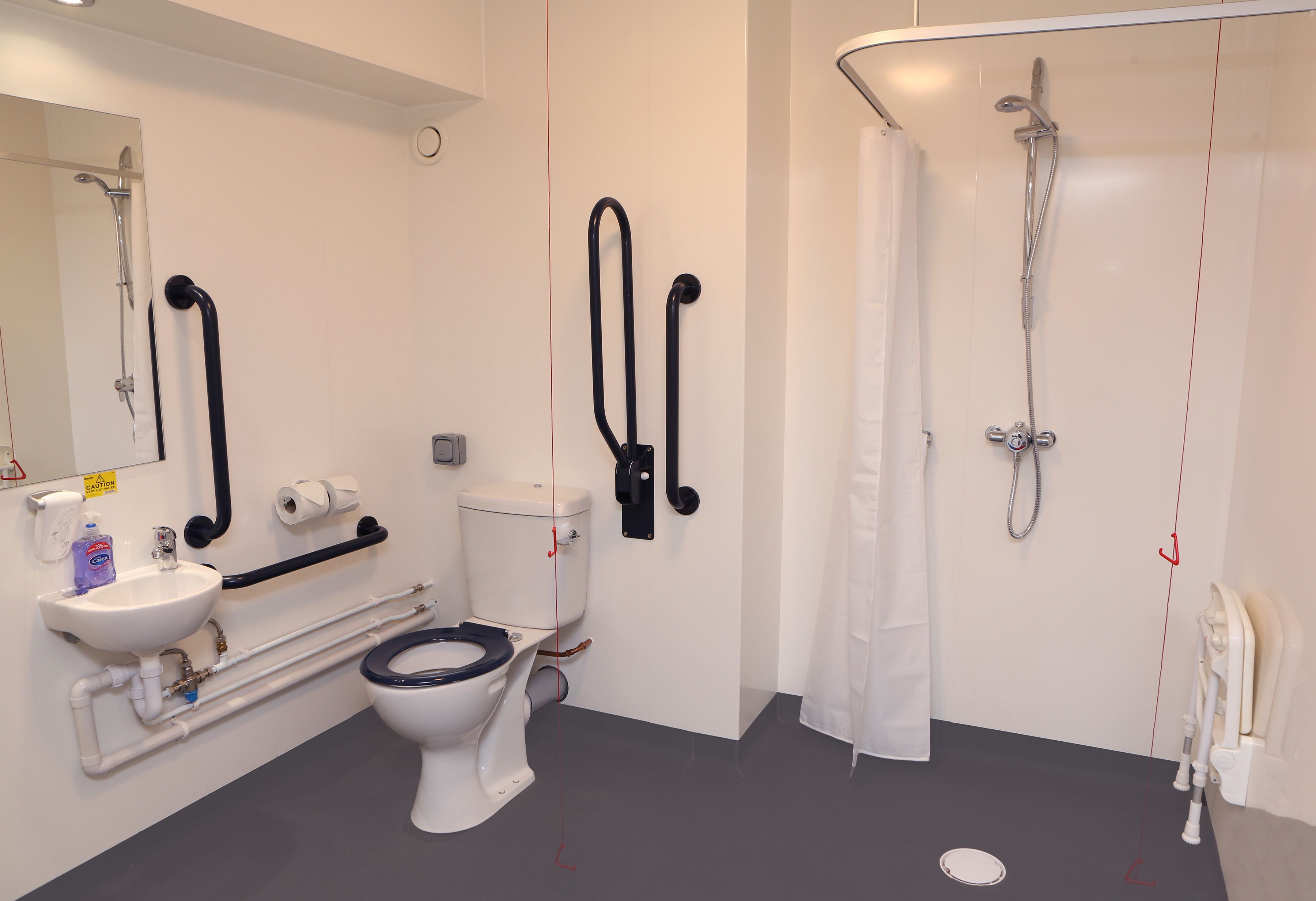 Une salle de bain moderne équipée de toilettes, d’un lavabo et d’une douche.