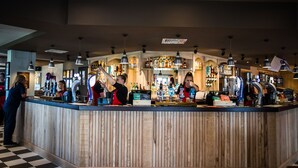 A bar area with a wooden counter, multiple taps, and a variety of bottles. - Harbour Spring, Peterhead by Marston's Inns (Peterhead)
