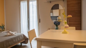 A hotel room with a bed, a dining table, a chair, a mirror, and a vase with flowers. - Residence Art (Rimini)