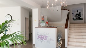 A reception area with a modern design, including a reception desk labeled "ART" and a staircase leading to an upper floor. - Residence Art (Rimini)
