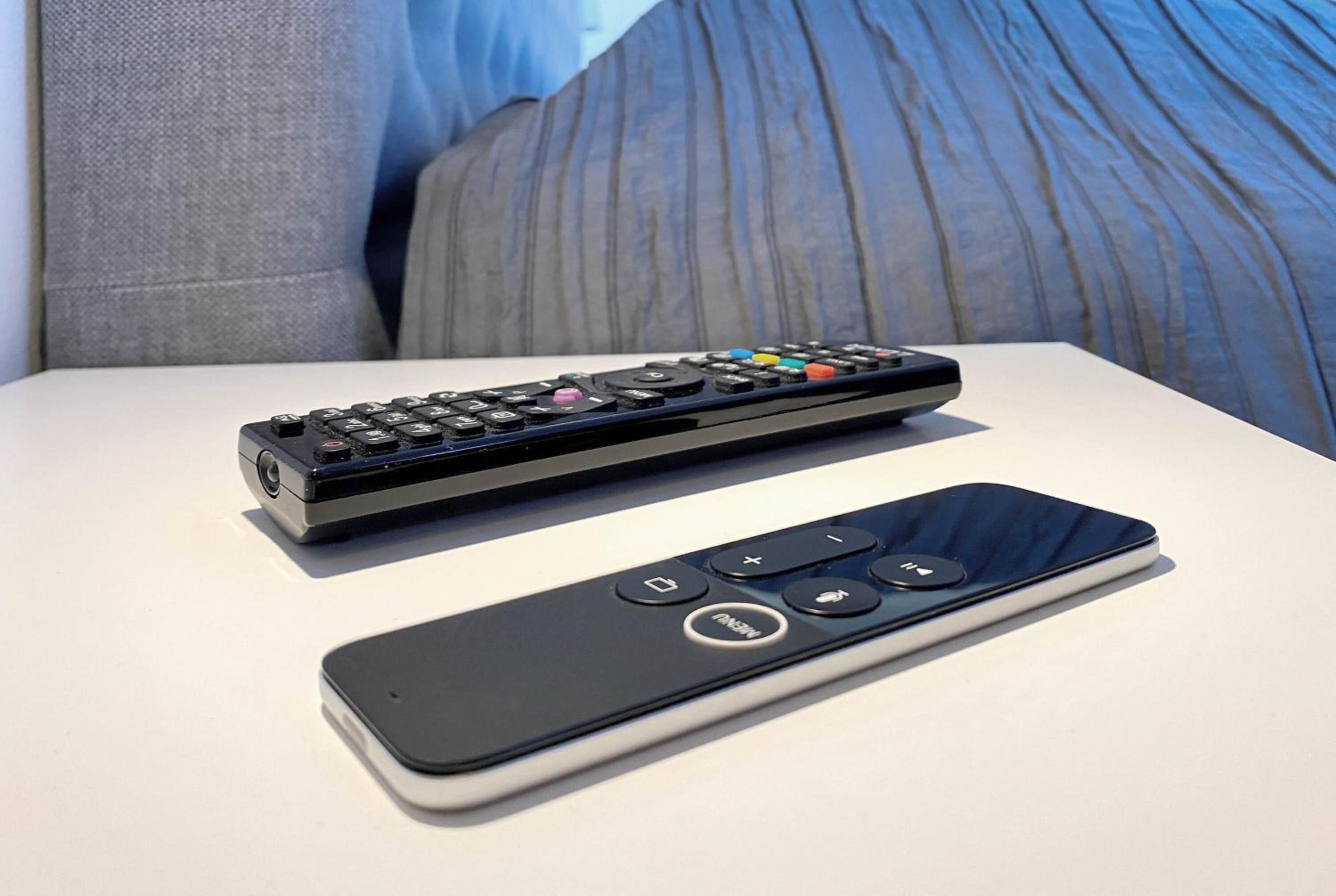 Um comando remoto e um smartphone sobre uma superfície branca.