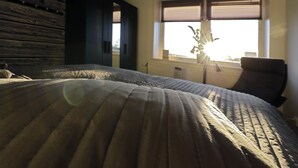 Un dormitorio con una cama grande, una silla y una ventana con persianas.