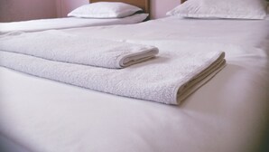 Two beds with white linens and pillows, and a folded white towel on the bed. - Villa Vera Mini Hotel (Tbilisi)