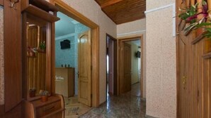 A hallway with wooden doors, a wooden bench, and a tiled floor. - Villa Vera Mini Hotel (Tbilisi)