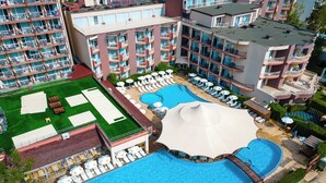 Ein Hotel mit mehreren Schwimmbecken, Liegestühlen und einer Dachterrasse.