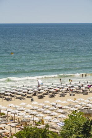 A beach with numerous umbrellas and sun loungers, a sandy shore, and the ocean in the background. - MPM Hotel Orel (Sunny Beach)