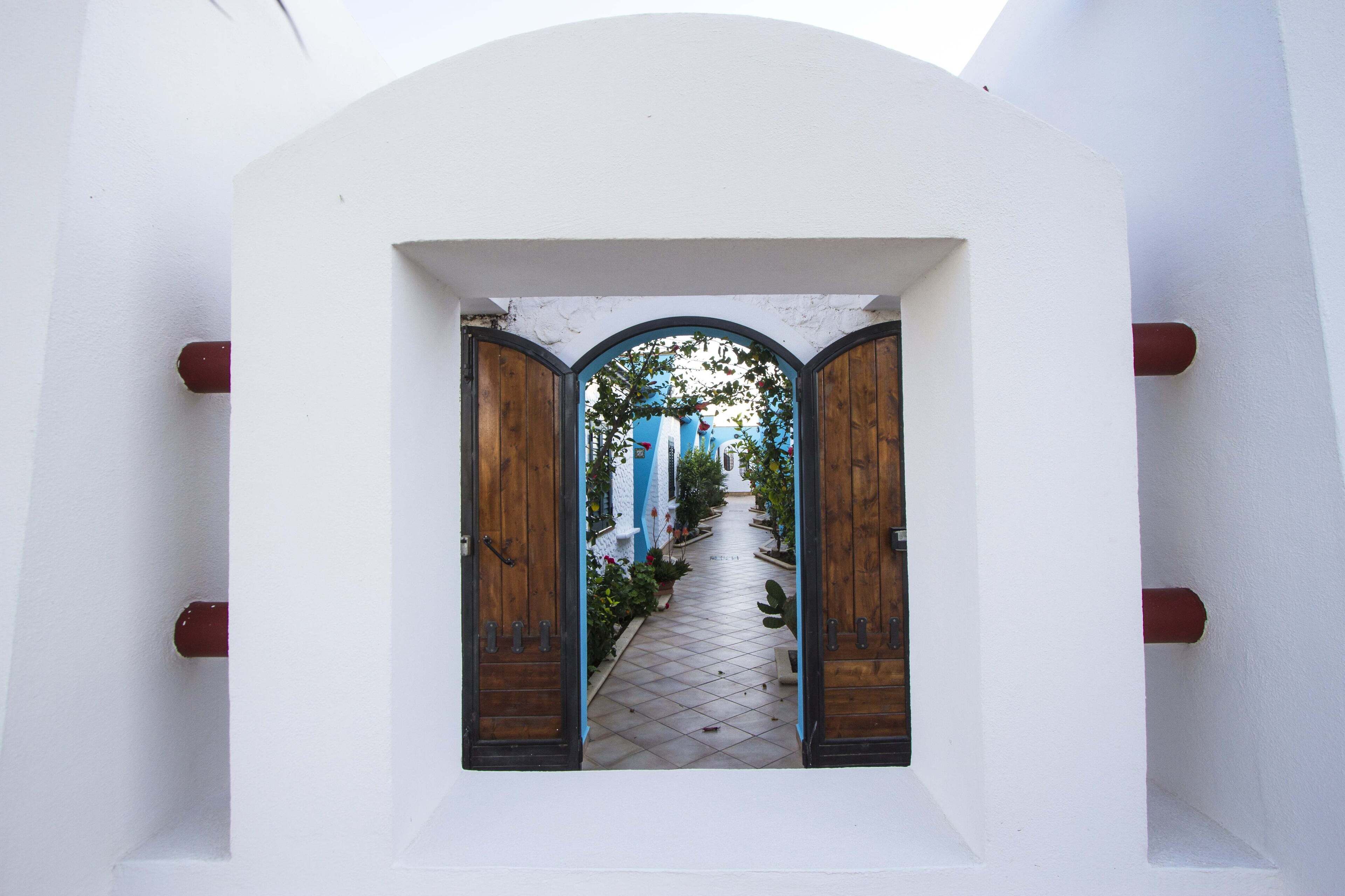 Un bâtiment blanc avec un étroit sentier menant à une porte en bois.