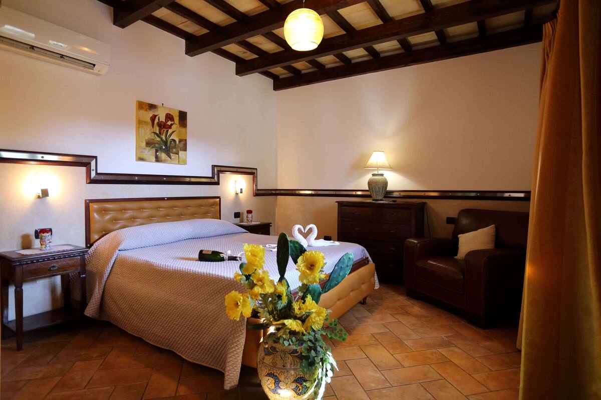 Una camera da letto con un letto, comodini, abat-jour e un vaso con fiori.