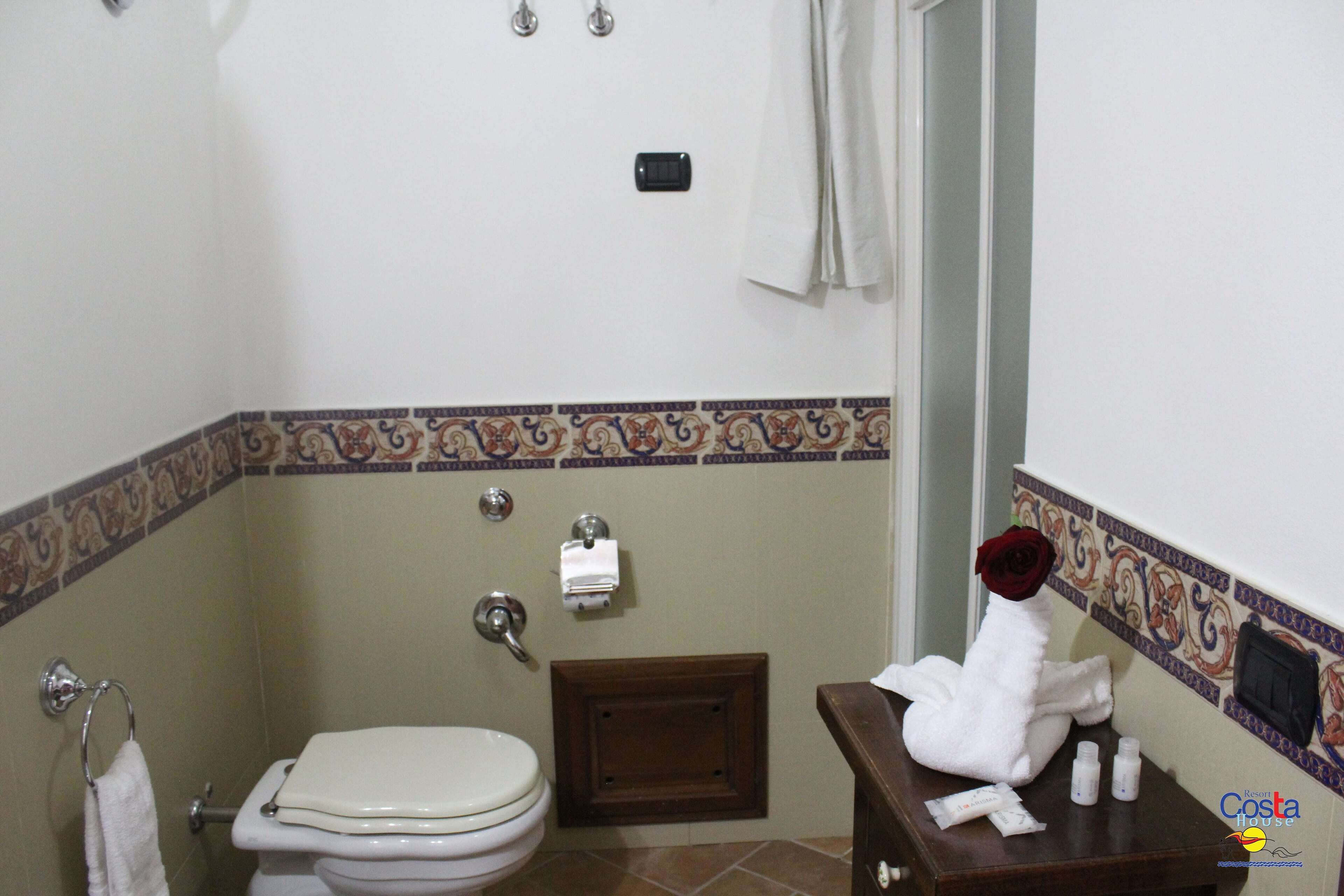 Un baño con inodoro, lavamanos y toallero.