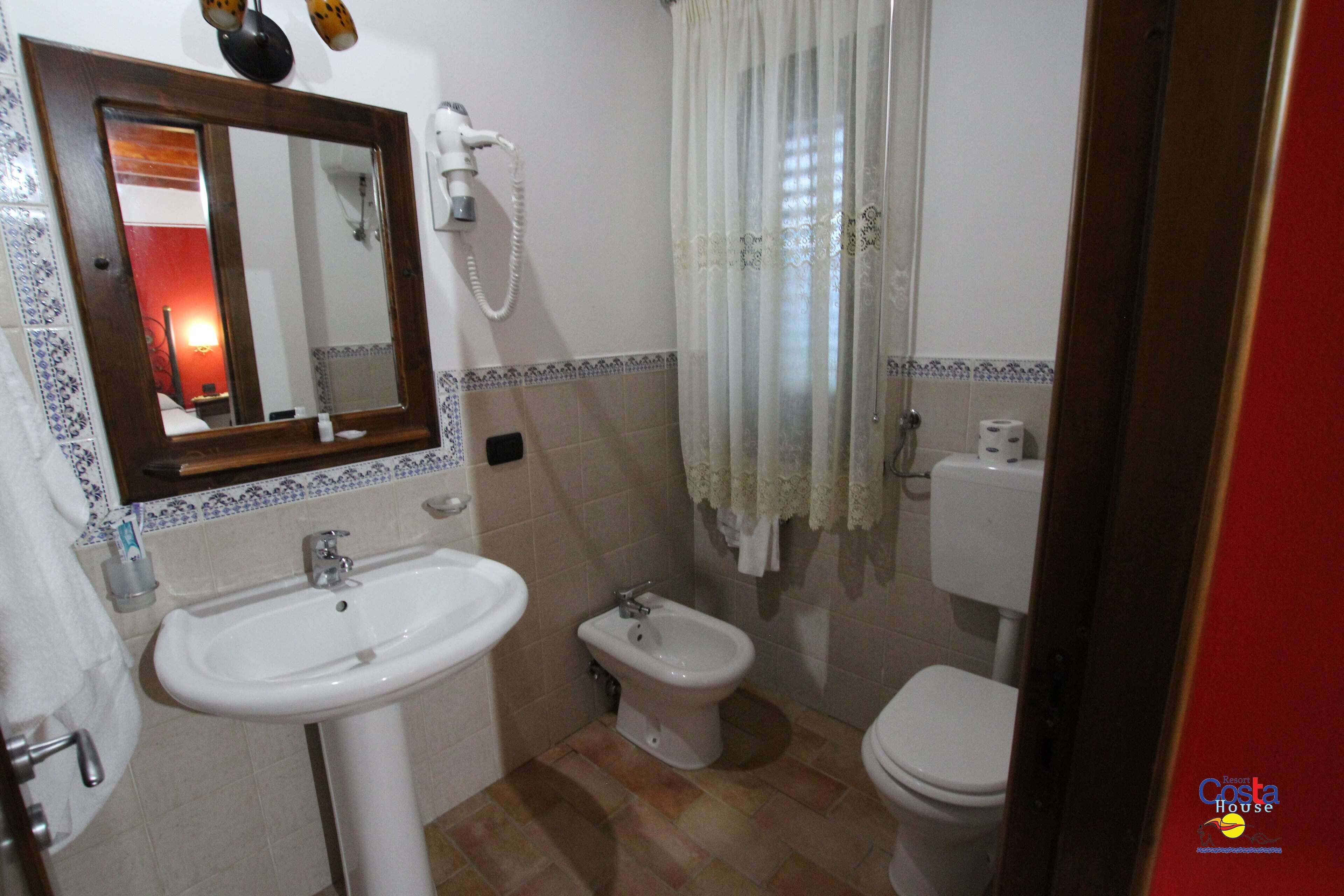 Un baño con lavamanos, bidé, inodoro y espejo.