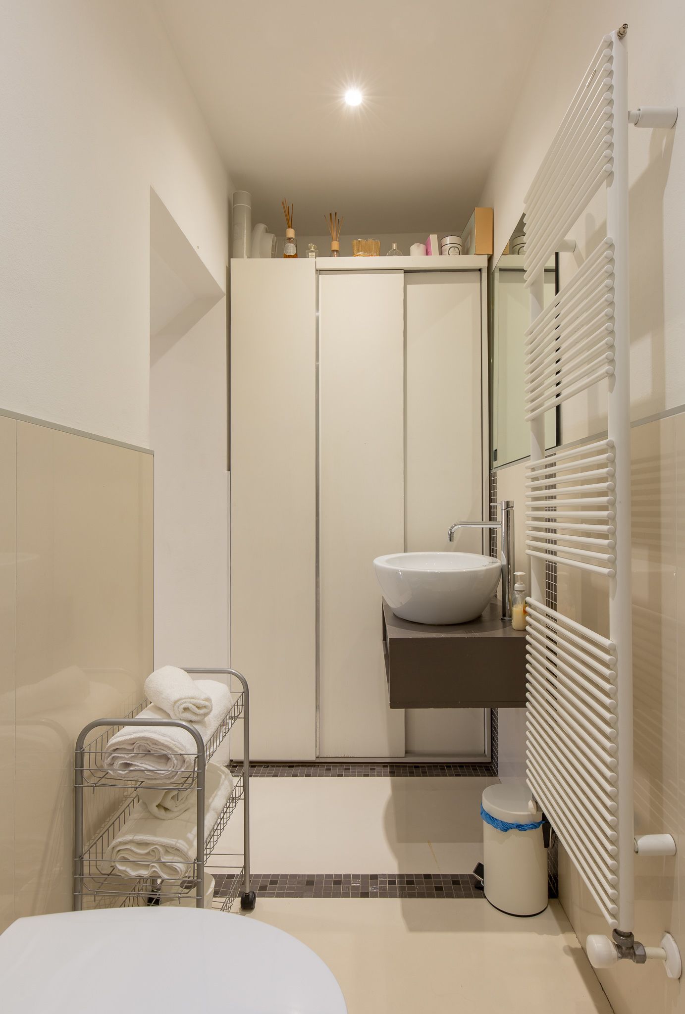 A modern bathroom with a white sink, a towel rack, and a toilet.