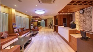 A hotel lobby with a reception desk, seating area, and a chandelier. - Hotel Prince Gardens (Coimbatore)