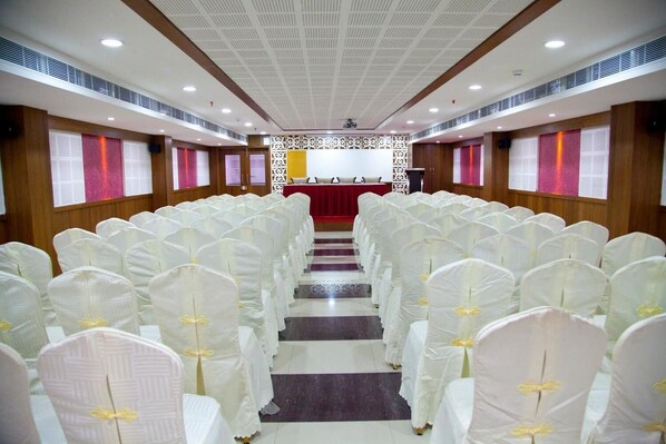 A church interior with rows of white chairs, a red altar, and wooden paneling. - Hotel Prince Gardens (Coimbatore)