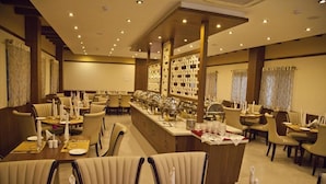 A hotel dining area with multiple tables, chairs, and a buffet setup. - Hotel Prince Gardens (Coimbatore)