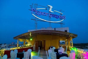 A covered outdoor area with a sign reading "Prince Gardens" and tables set up for an event. - Hotel Prince Gardens (Coimbatore)
