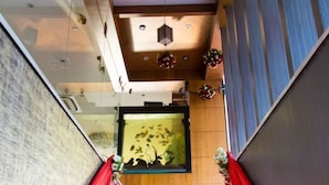 A staircase with red drapes, wooden beams, and a wall-mounted decorative piece. - Hotel Prince Gardens (Coimbatore)